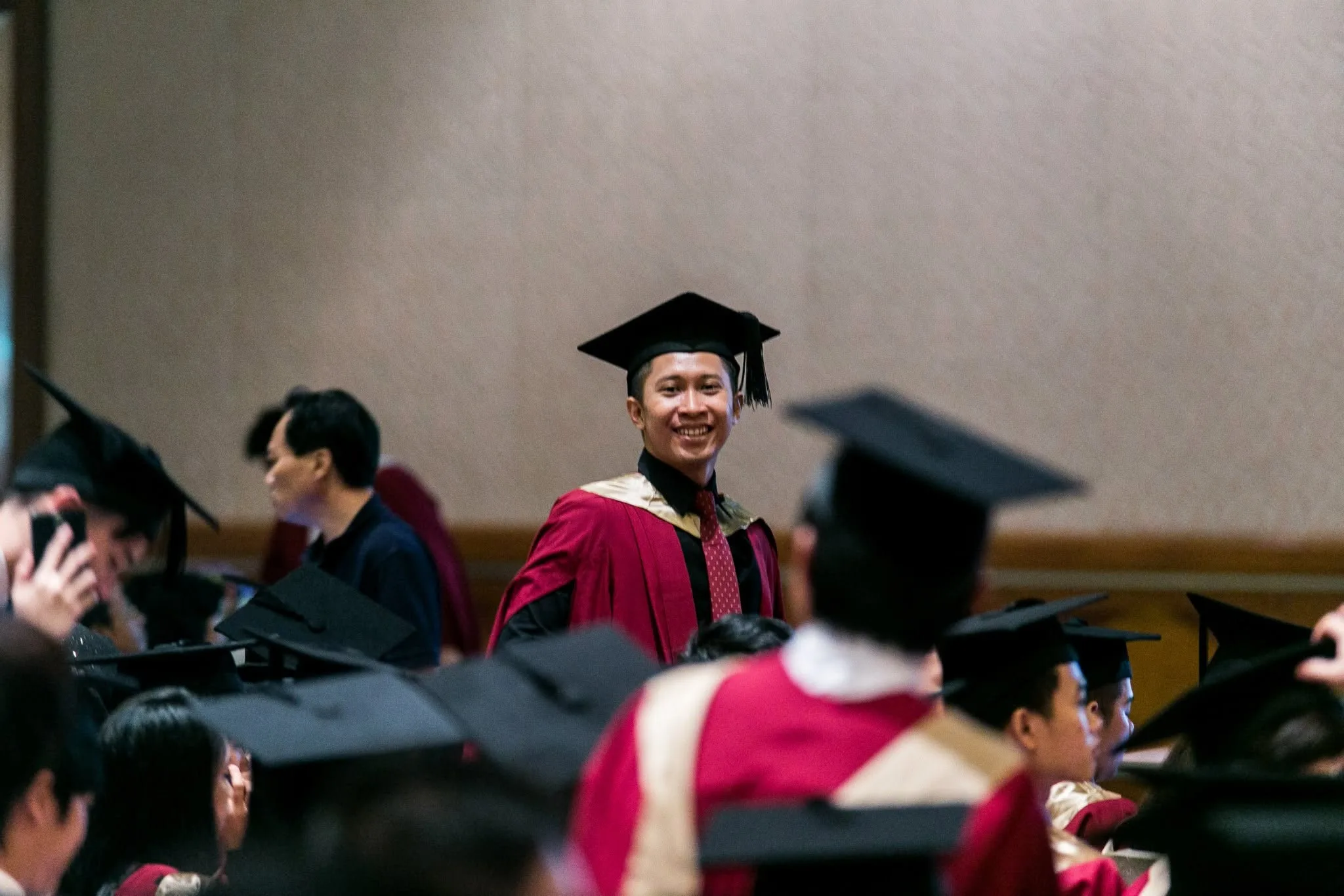 Nazreen Daud smiling among fellow graduates in a red gown and mortarboard at his Murdoch University graduation