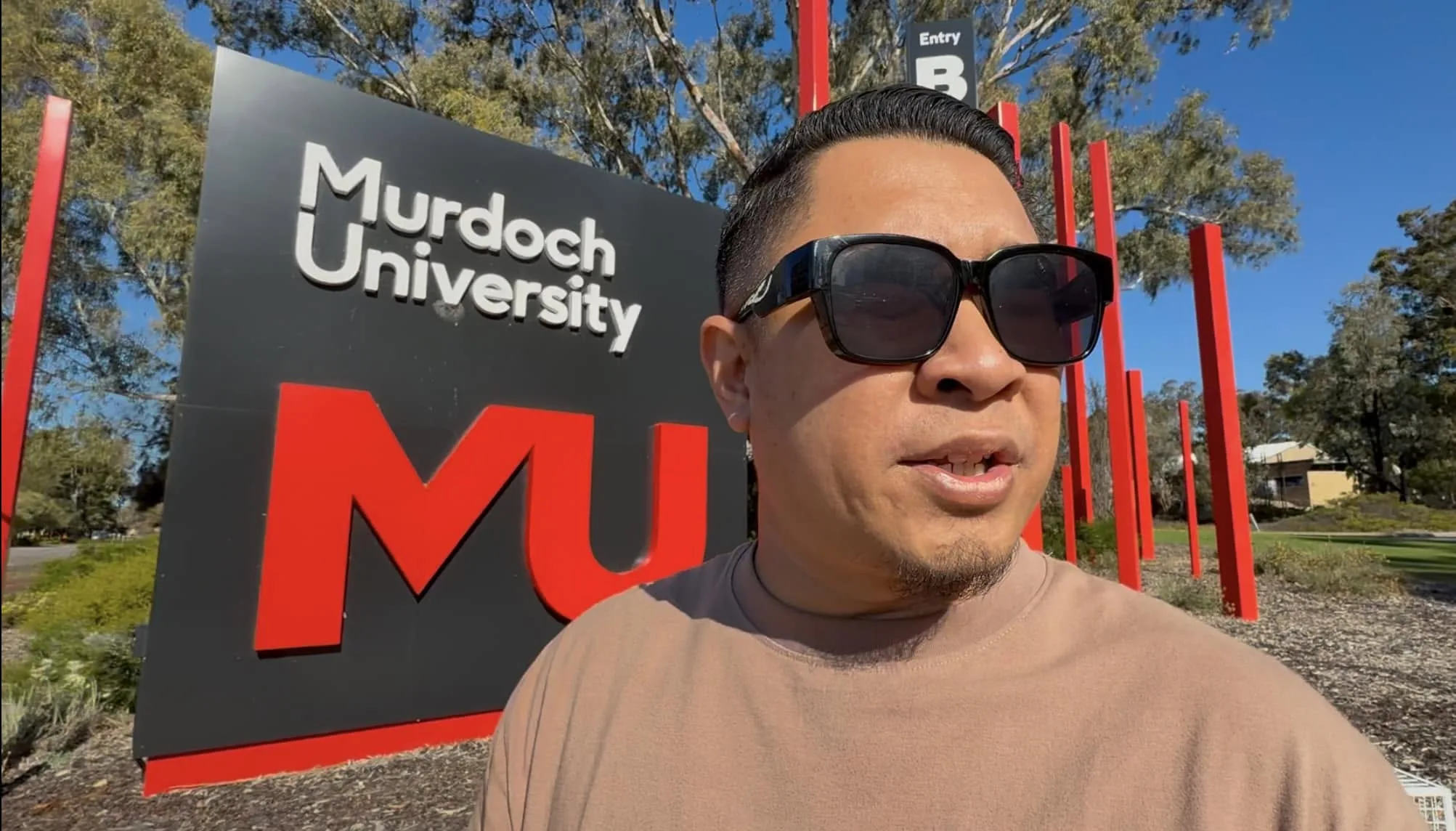 Nazreen Daud revisiting the Murdoch University campus, standing beside the university's entrance sign