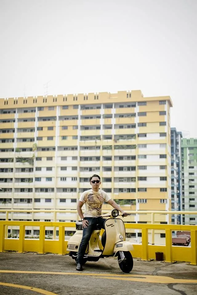 Nazreen Daud on his cream Vespa Super 150 in a rooftop car park, with the Sim Lim flats behind him